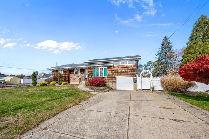 View of front of home featuring a front lawn, driveway, an attached garage, and a gate