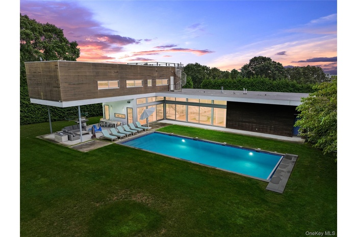 Pool at dusk with a lawn, an outdoor hangout area, an outdoor pool, and a patio area