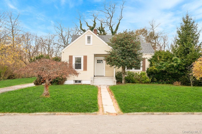 View of front of house featuring a front yard, a chimney, and roof with shingles