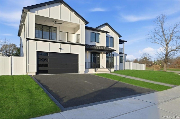 Modern farmhouse featuring board and batten siding, a standing seam roof, driveway, a metal roof, and an attached garage