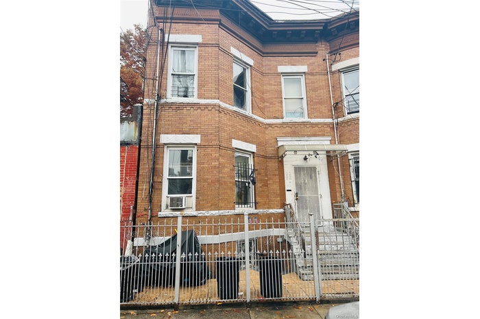 View of front facade featuring brick siding, a fenced front yard, and cooling unit