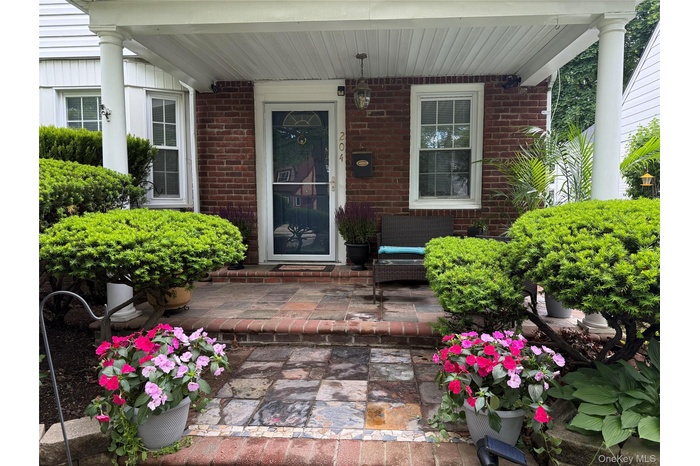 View of exterior entry with brick siding and covered porch