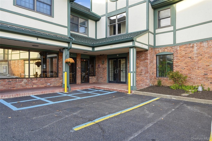 Property entrance with stucco siding, uncovered parking, and brick siding