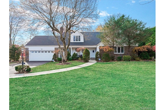 View of front of property with a front yard, covered porch, driveway, and an attached garage