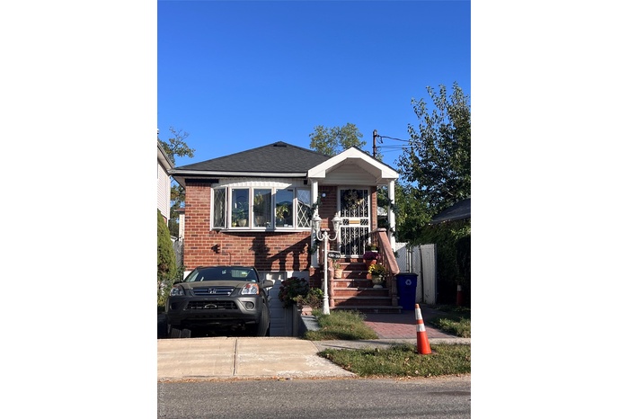 View of front of property featuring brick siding and roof with shingles