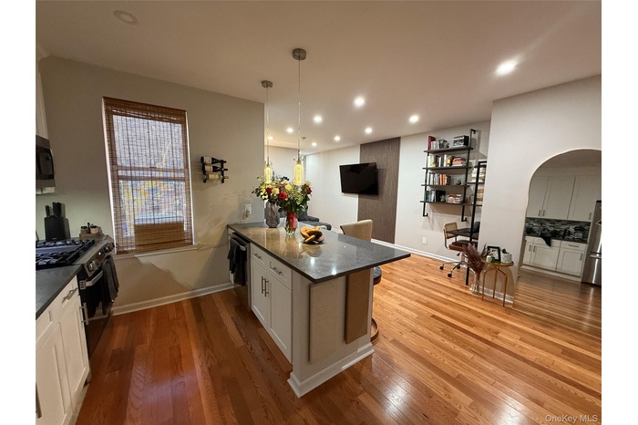 Kitchen with a kitchen bar, white cabinets, dark stone counters, hanging light fixtures, and a peninsula