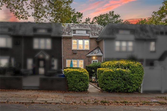 View of front of home with brick siding and mansard roof