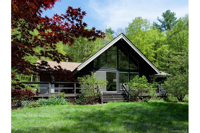 Rear view of house with a lawn, a wooden deck, and a sunroom