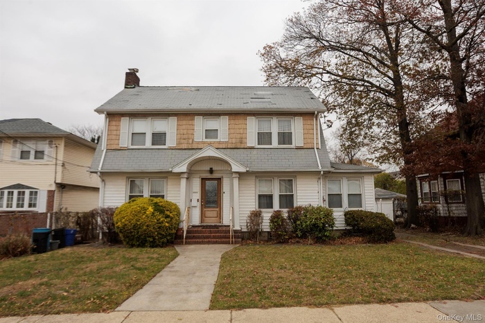View of front of house featuring a chimney and a front lawn