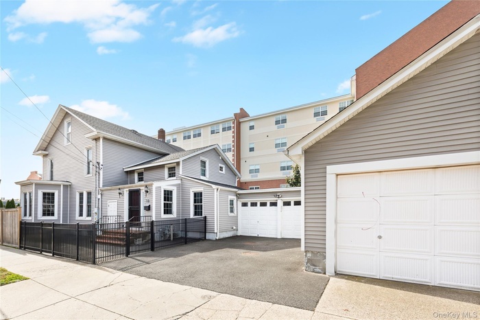 View of front of house with a garage, a fenced front yard, and asphalt driveway