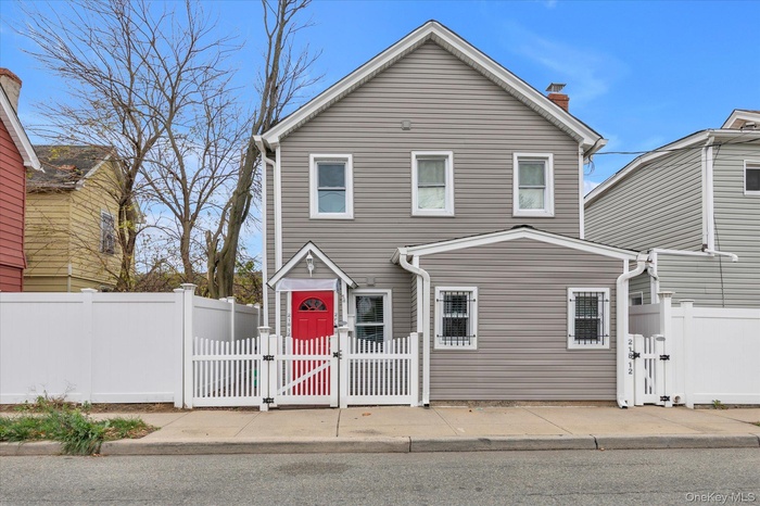 Traditional-style home featuring a gate, a fenced front yard, and a chimney