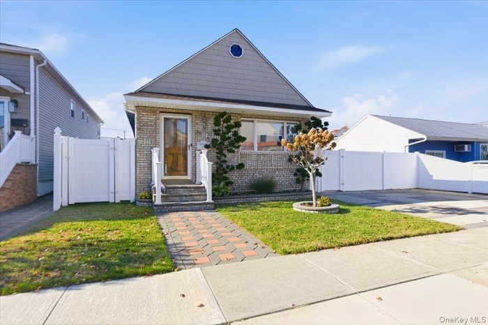 View of front of home with a gate and brick siding
