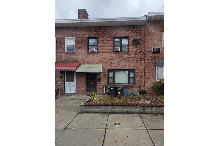 View of front of house with brick siding, a chimney, and a wall unit AC
