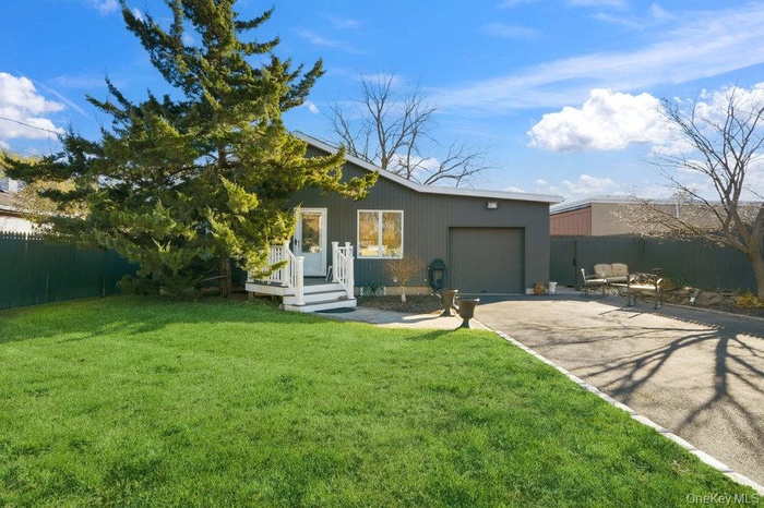 Back of house featuring driveway, a patio area, and an attached garage