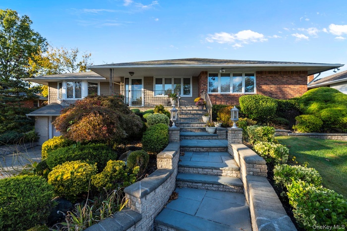 View of front of house featuring covered porch, brick siding, and stairs
