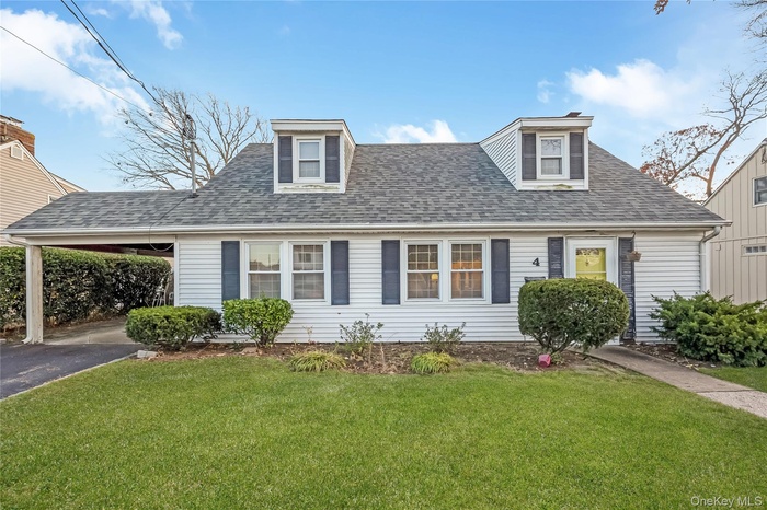 View of front facade with a front lawn, roof with shingles, and an attached carport