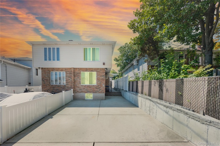 Back of property at dusk featuring a fenced backyard, a patio, and brick siding