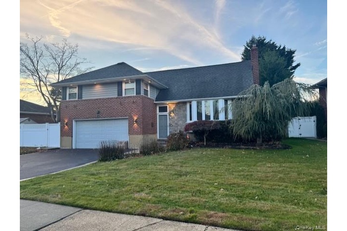 Expanded Split level home with a gate, driveway, a garage, and a chimney