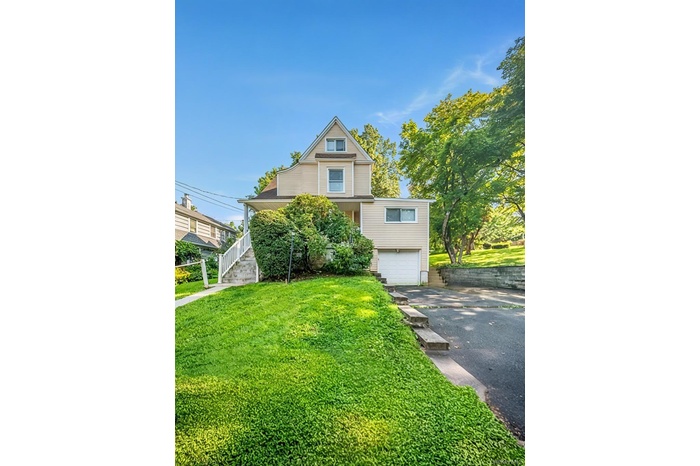 View of front of property with driveway, a garage, a front lawn, and stairs