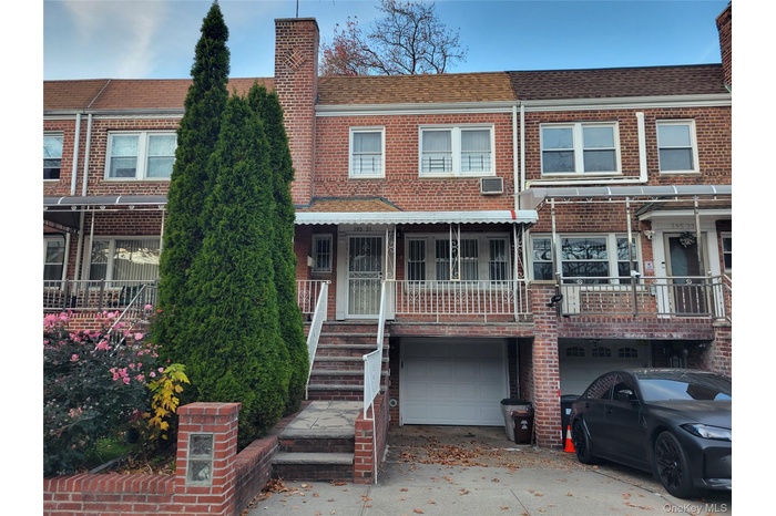 Traditional home featuring a shingled roof, concrete driveway, a garage, a chimney, and covered porch
