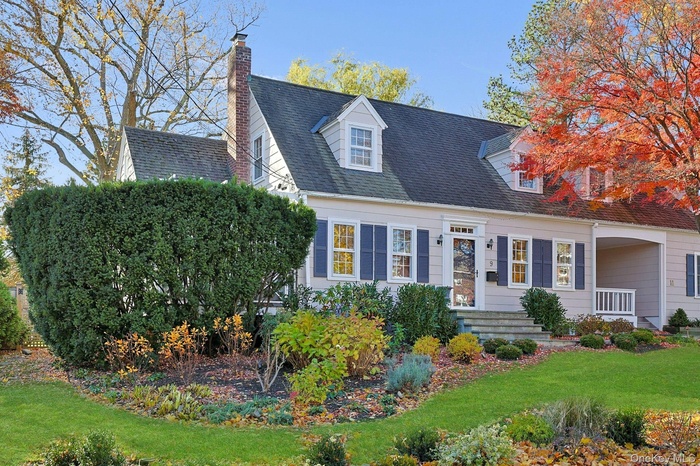 Cape cod house featuring a front yard, a chimney, and a shingled roof