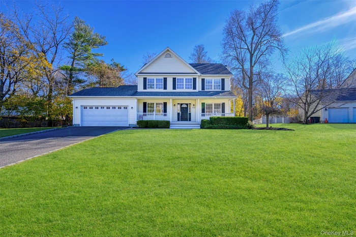 View of front of property with a porch, a front yard, driveway, and a garage