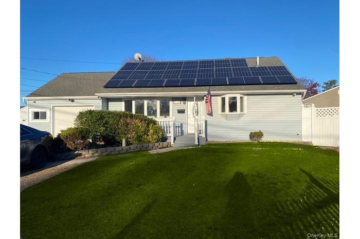 View of front facade with a front lawn, a garage, and solar panels