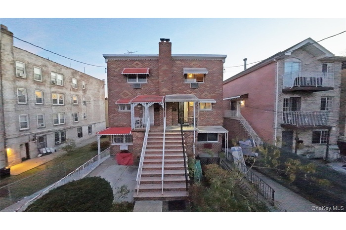Back of property with stairs, brick siding, a chimney, and a balcony