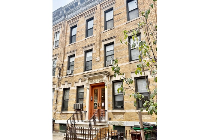 View of building exterior with a fenced front yard and cooling unit