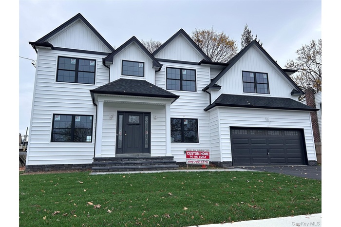 Modern farmhouse featuring a front lawn, an attached garage, roof with shingles, driveway, and board and batten siding