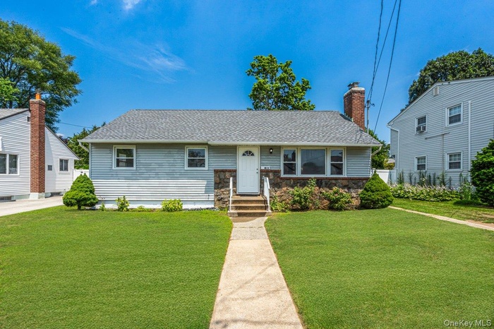 Ranch with a chimney, stone siding, and a shingled roof