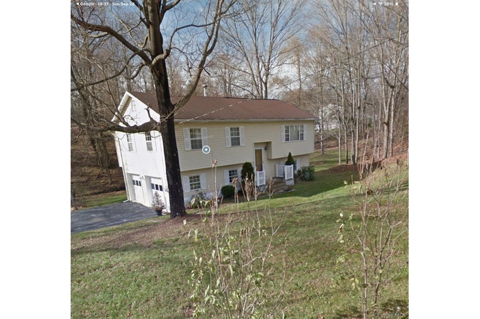 View of front of house featuring a front lawn, asphalt driveway, and an attached garage