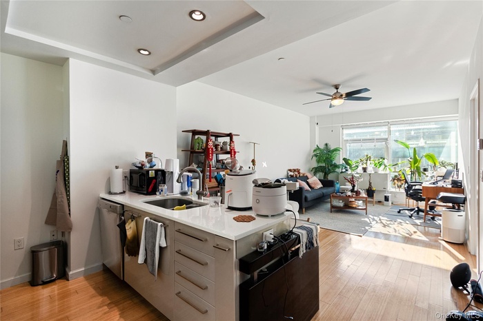 Kitchen featuring a peninsula, light wood finished floors, light stone counters, modern cabinets, and ceiling fan