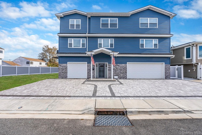 Traditional-style home featuring stone siding, decorative driveway, and a garage