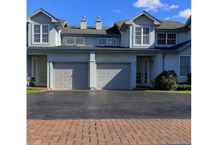 Traditional-style house featuring stucco siding, asphalt driveway, a chimney, and an attached garage