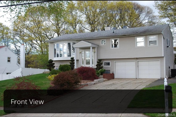 Bi-level home with a garage, cooling unit, fence, a chimney, and driveway