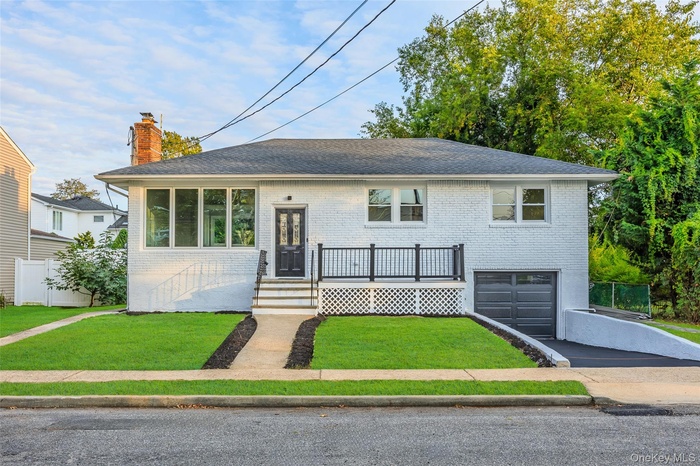 View of front of house featuring driveway, brick siding, roof with shingles, an attached garage, and a chimney