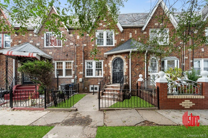 Tudor-style house featuring a gate, a fenced front yard, and brick siding
