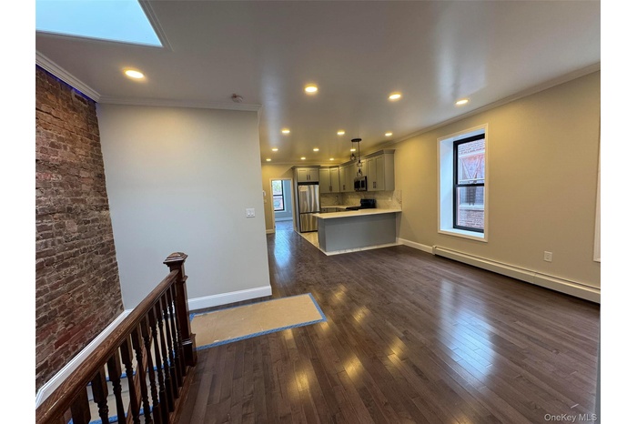 Kitchen with light countertops, plenty of natural light, ornamental molding, a peninsula, and baseboard heating