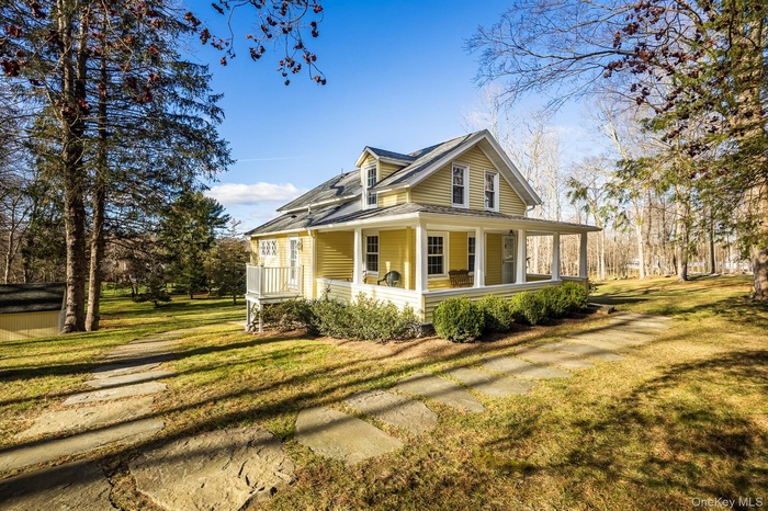 Country-style home featuring a porch, a front yard, and a shingled roof