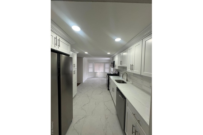 Kitchen with fridge, white cabinetry, stove, light marble finish floors, and recessed lighting