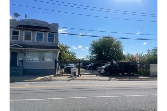 View of asphalt street featuring sidewalks, a gate, and curbs