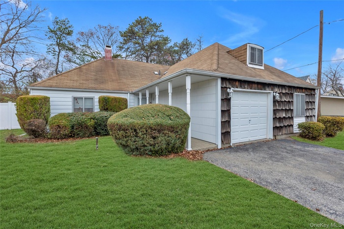 View of side of home featuring a garage, driveway, a chimney, and roof with shingles