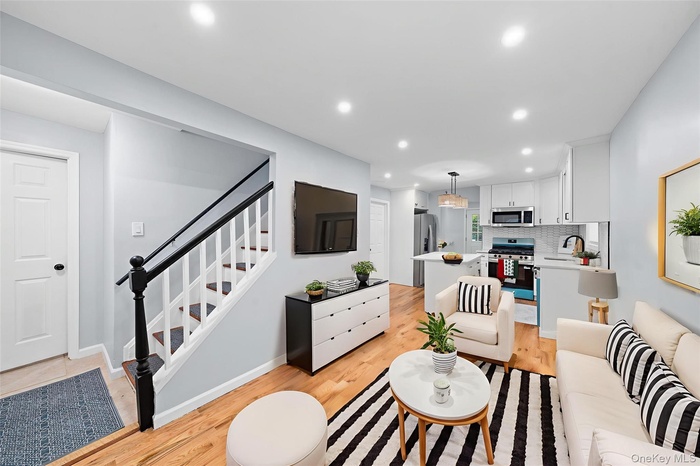 Living area with light wood finished floors, stairs, and recessed lighting