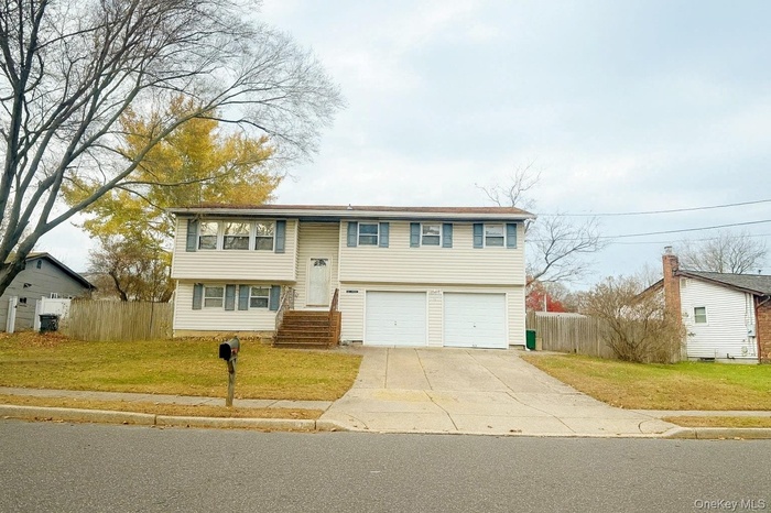 Split foyer home featuring concrete driveway and a garage