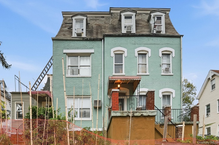 Second empire-style home featuring stairs, mansard roof, brick siding, and a shingled roof