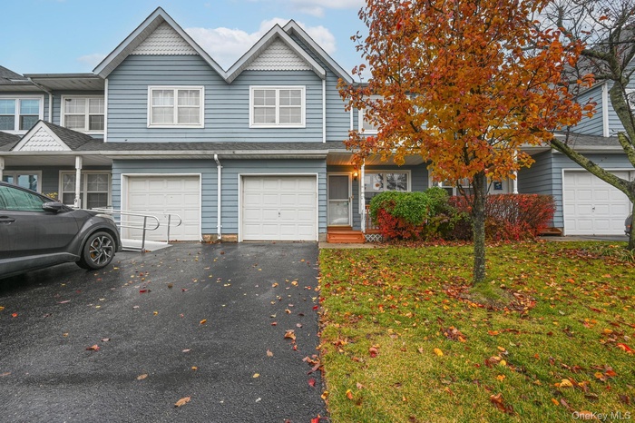View of front of home featuring driveway, a front yard, an attached garage, and a shingled roof