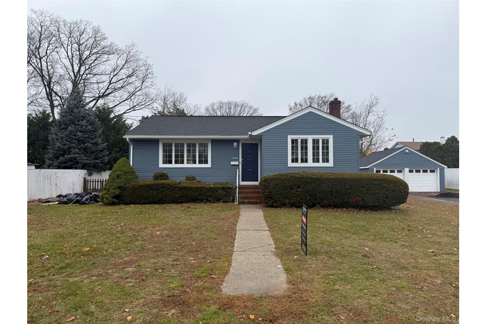 View of front of home with a garage, a chimney, and an outdoor structure