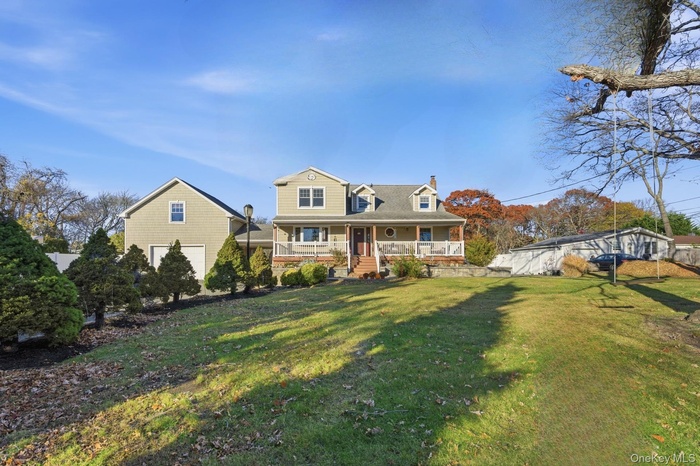 View of front of house featuring covered porch, a chimney, and a front lawn