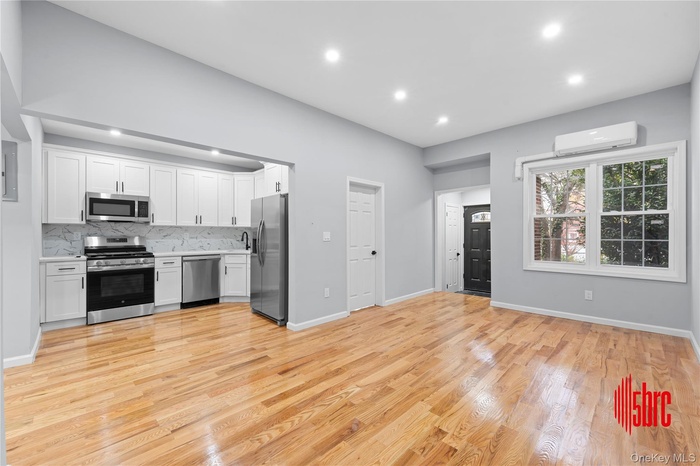 Kitchen featuring white cabinets, appliances with stainless steel finishes, open floor plan, light wood-type flooring, and recessed lighting